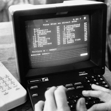 Ancien ordinateur avec écran noir et texte blanc, mains sur le clavier.