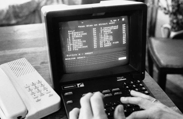 Un ordinateur ancien avec un écran affichant du texte, des mains tapant sur le clavier.