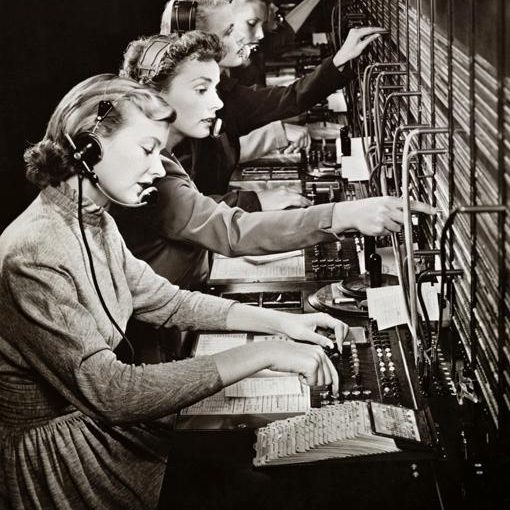 Échangeons sur vos besoins Trois femmes opératrices téléphoniques utilisant des commutateurs dans un bureau.