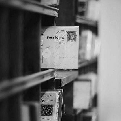 Cartes postales anciennes rangées sur des étagères en bois.