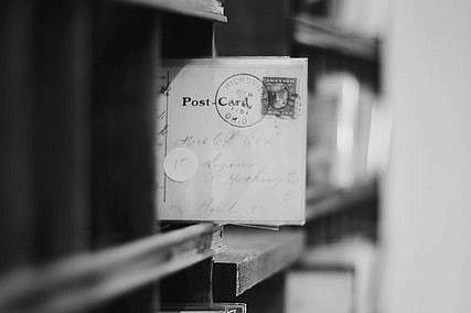 Cartes postales anciennes sur une étagère, légèrement floues en arrière-plan.