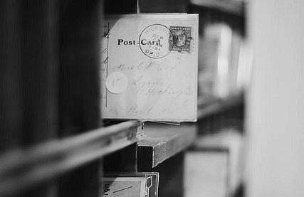 Cartes postales anciennes entreposées sur une étagère en bois.