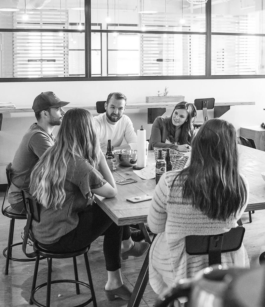 Groupe de personnes assises autour d'une table, discutant dans un espace lumineux.