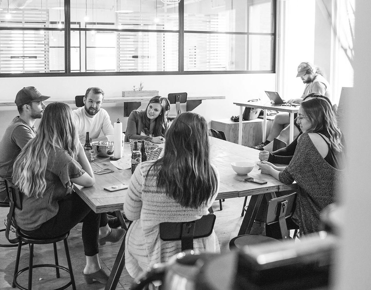 Groupe de personnes assises autour d'une table, discutant dans un espace de travail.