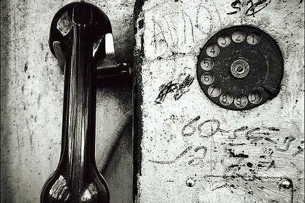 Ancien combiné de téléphone noir à côté d'un cadran en métal et de graffitis.