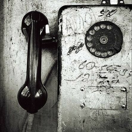 Téléphone vintage noir et blanc avec un cadran sur un mur usé.