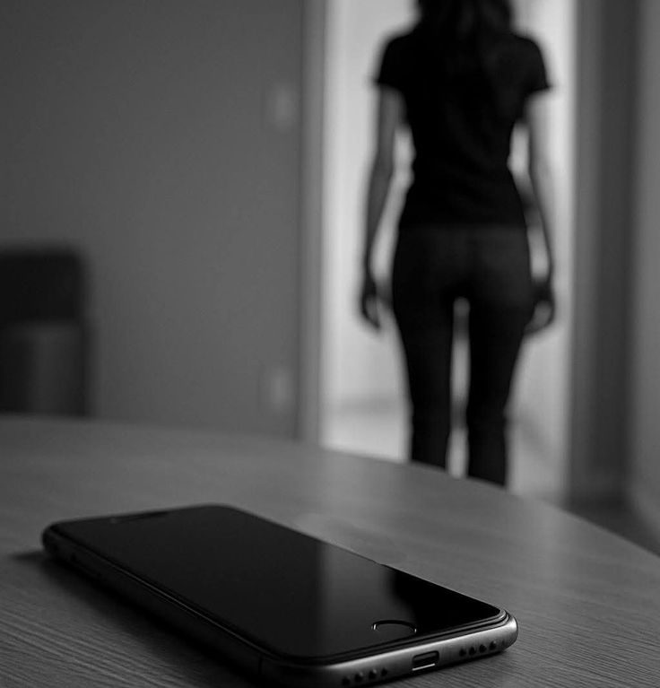 Un smartphone posé sur une table, avec une silhouette floue d'une personne en arrière-plan.